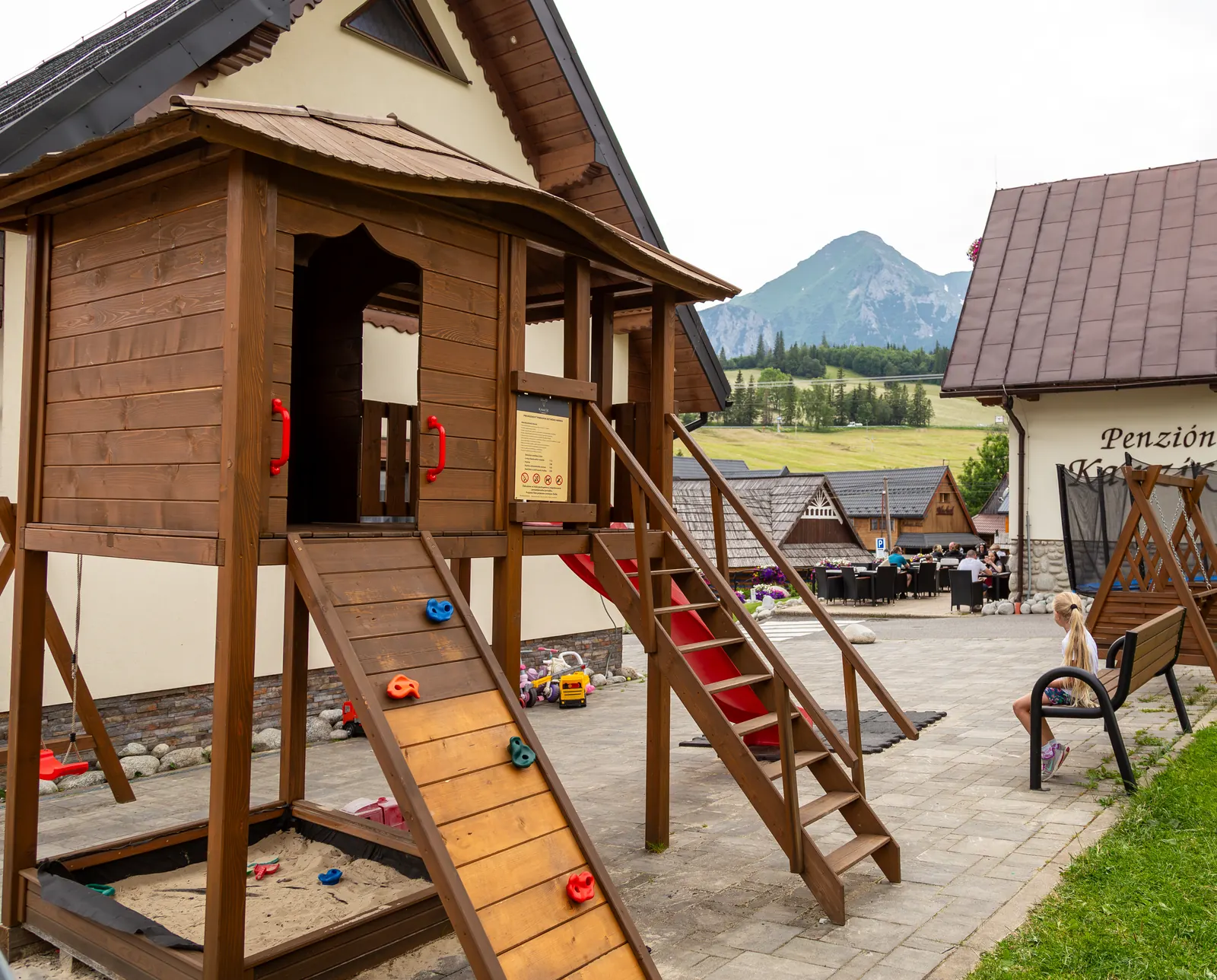 Children's playground with a playhouse, slide and sandpit, the Tatras in the background