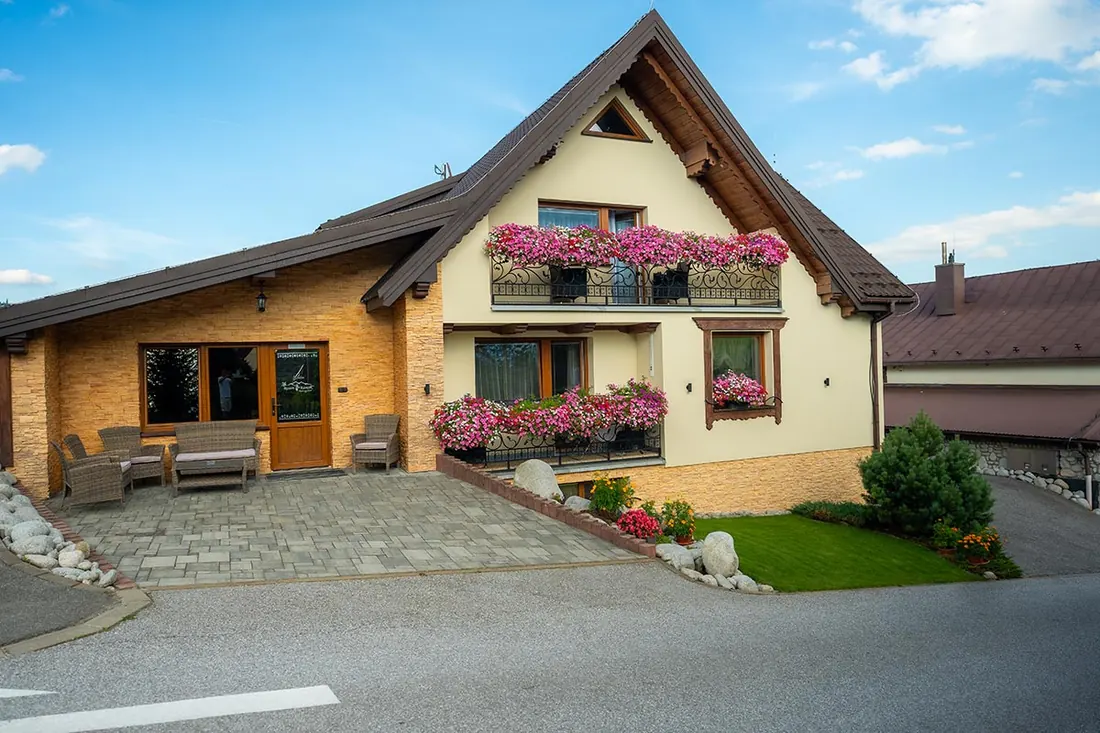 Villa Kamzík spredu, vchod s terasou a kvetmi na balkónoch
