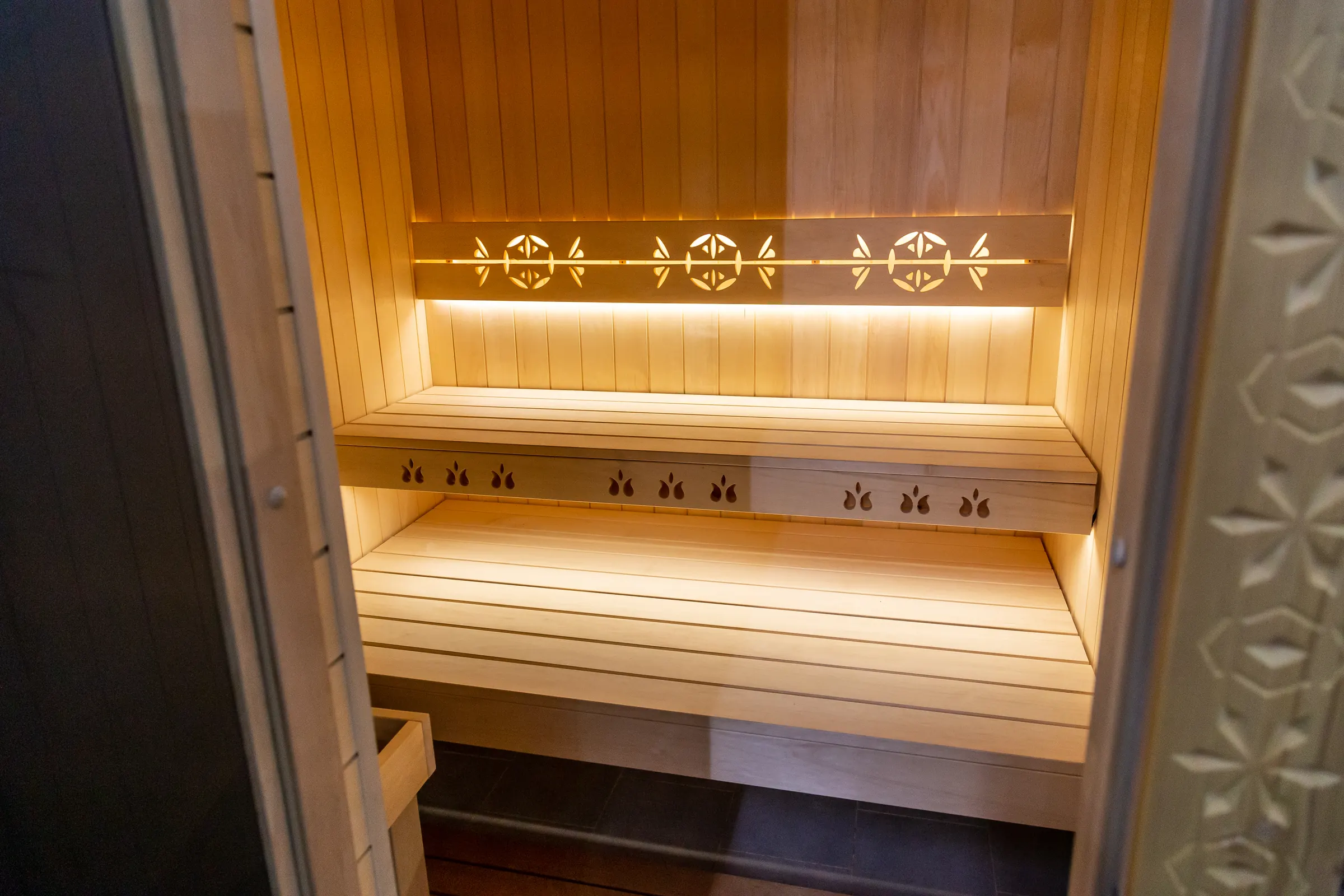 Fínska sauna s podsvietenými lavicami a vyrezávaným motívom